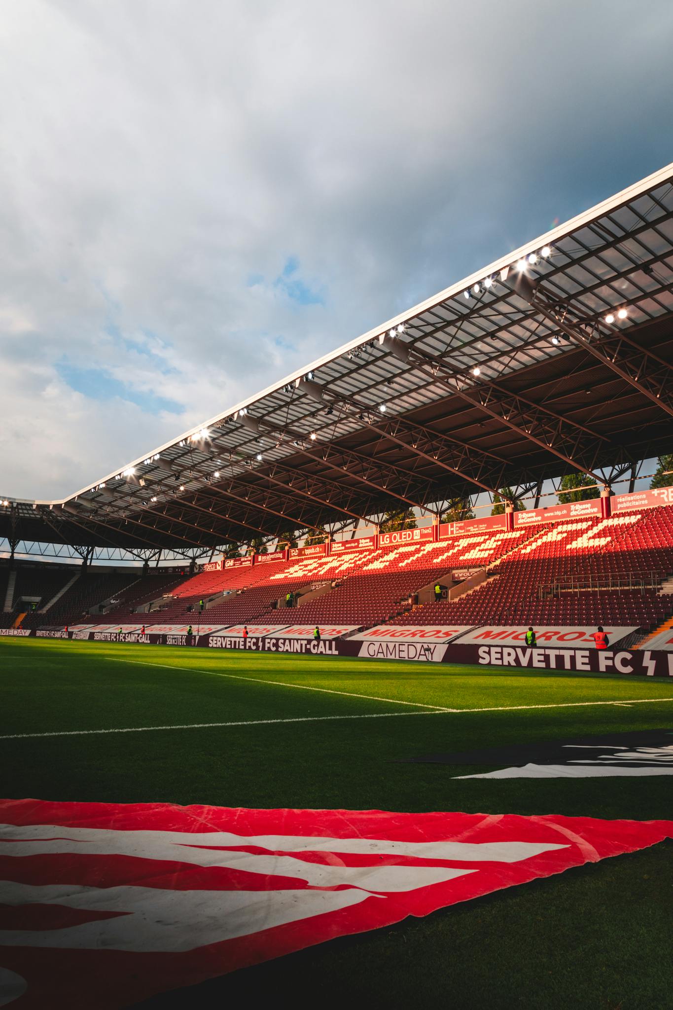 A view of Stade de Genève with empty grandstands during dusk, perfect for sports events and tournaments.