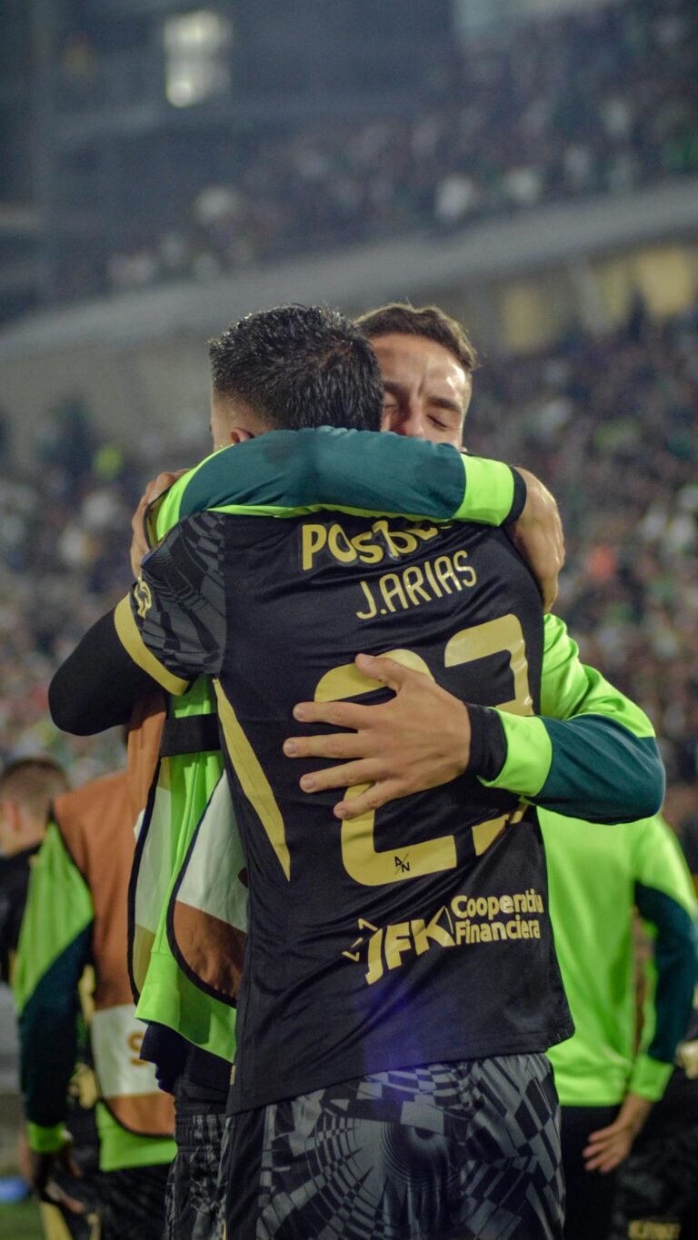 Emotional hug between two soccer players on the field after a game-winning goal.