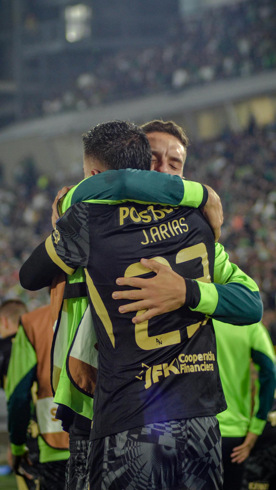 Emotional hug between two soccer players on the field after a game-winning goal.