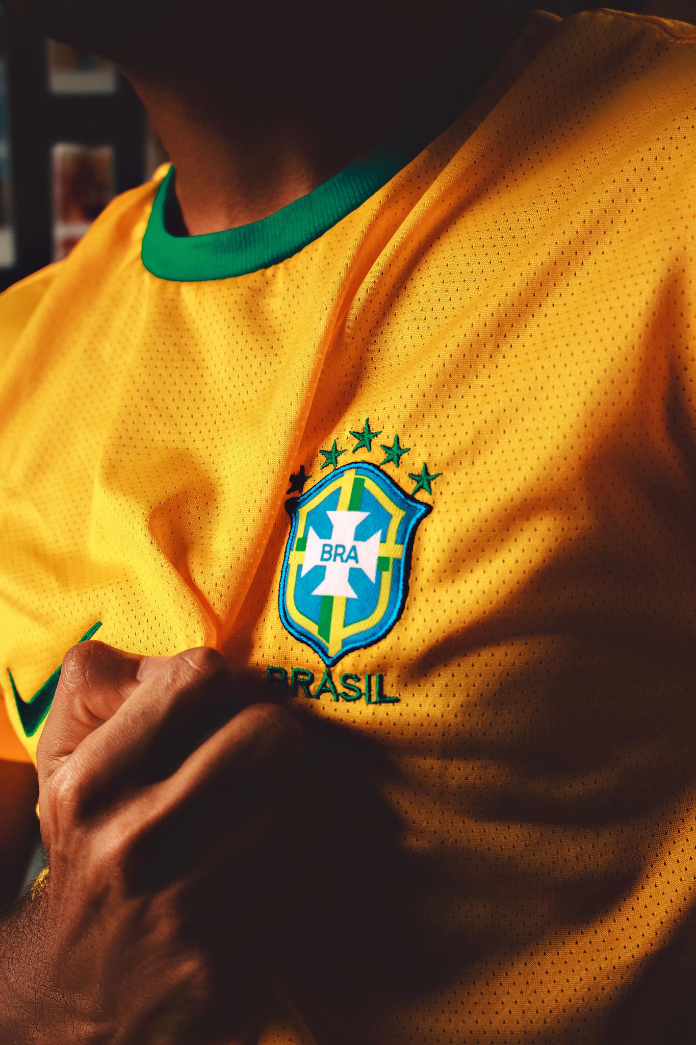 Focused close-up of a person holding Brazil soccer jersey with emblem.