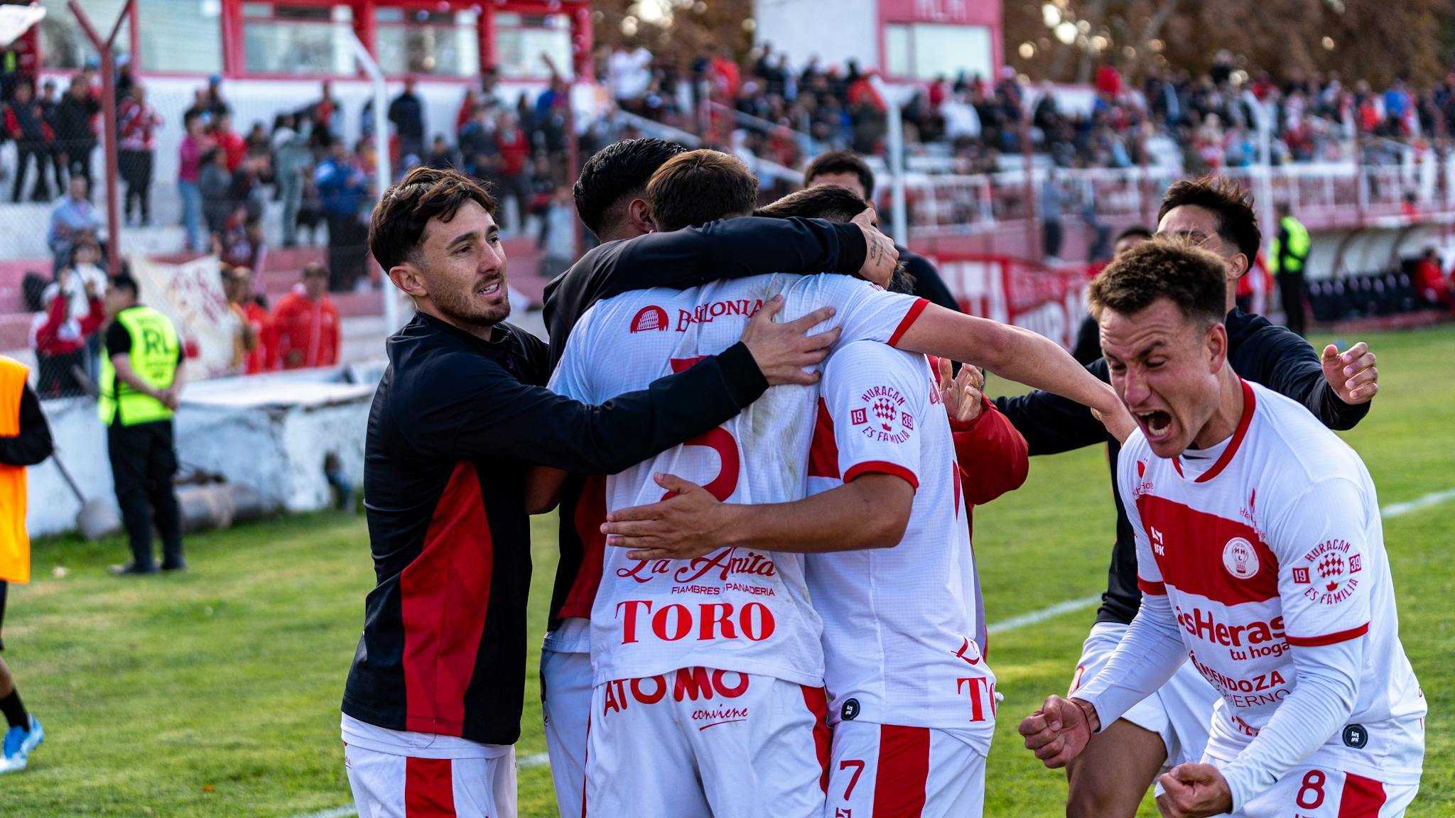 Players rejoice after a triumphant moment at an outdoor football game, conveying a sense of teamwork and achievement.